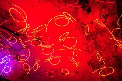 Abstract neon art metal poster with vivid colors illuminating a dark living room wall.