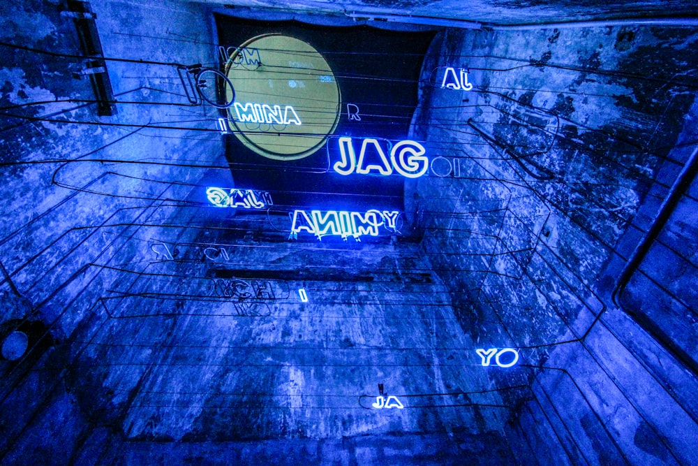 a blue tunnel with neon signs on the walls