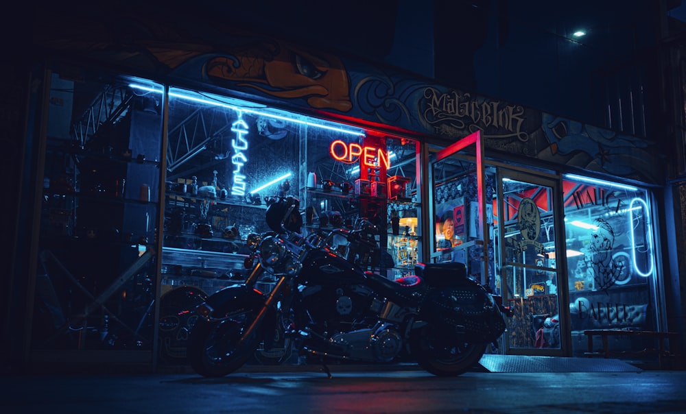 Motocicleta negra estacionada al lado de la tienda durante la noche