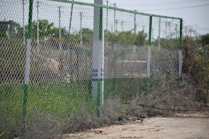 A neat row of chain link fence posts being installed with the tractor’s help