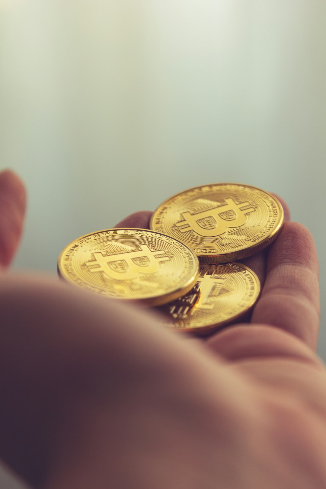 gold round coin on persons hand