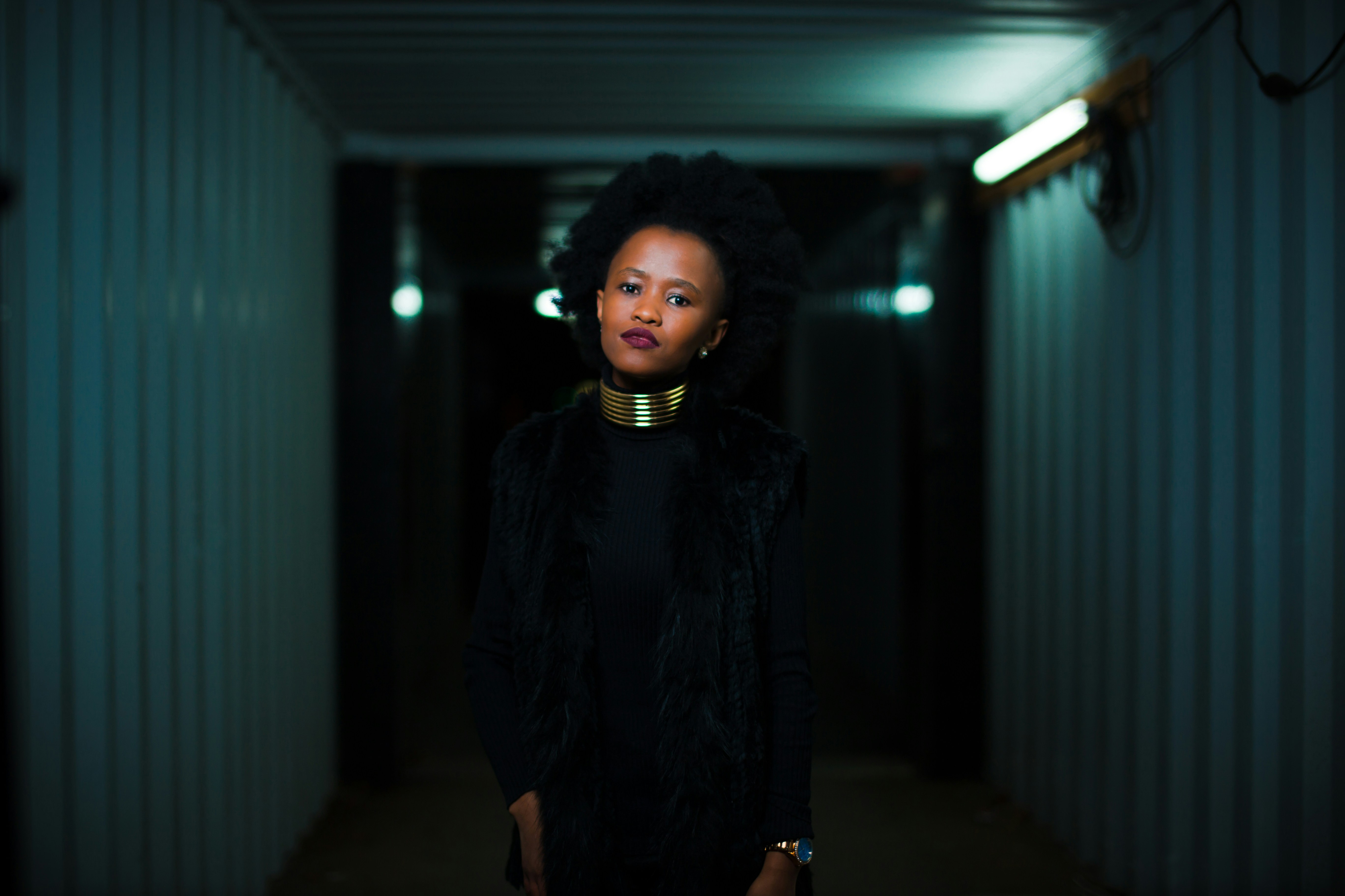 woman in black coat standing near gray wall