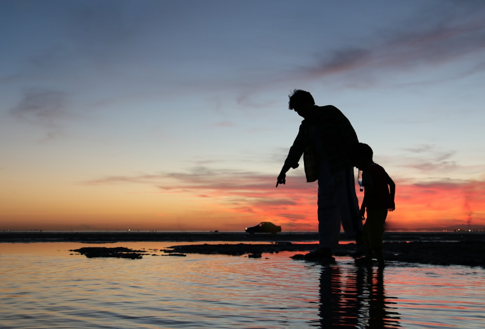 silhueta do homem e da mulher que se beijam na praia durante o pôr do sol