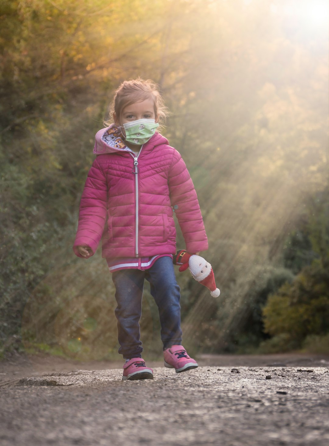 girl in pink zip up jacket standing on gray concrete road during daytime