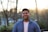 man in blue dress shirt standing near trees during daytime