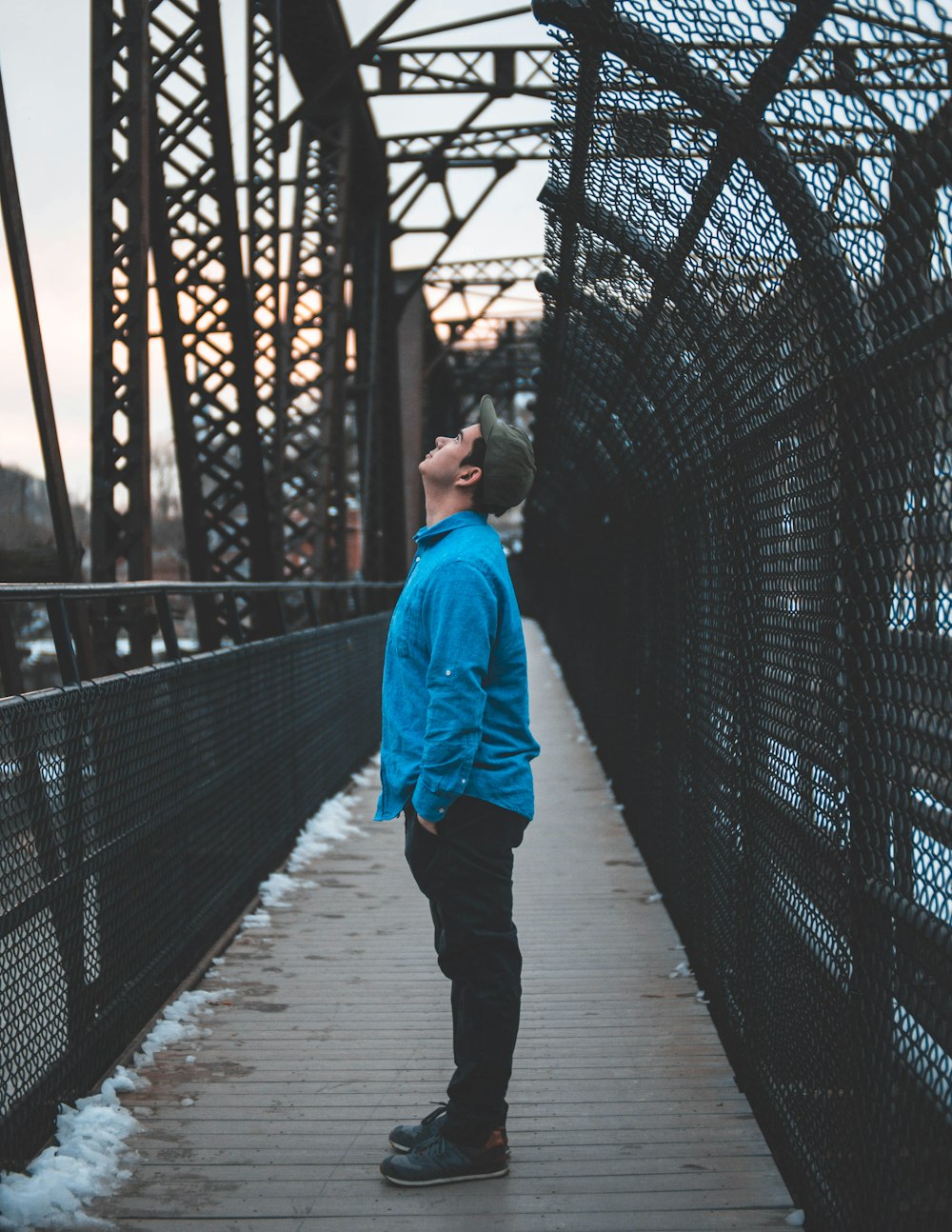 man in blue hoodie walking on bridge during daytime