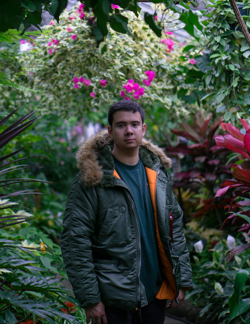 woman in black leather jacket standing near pink flowers