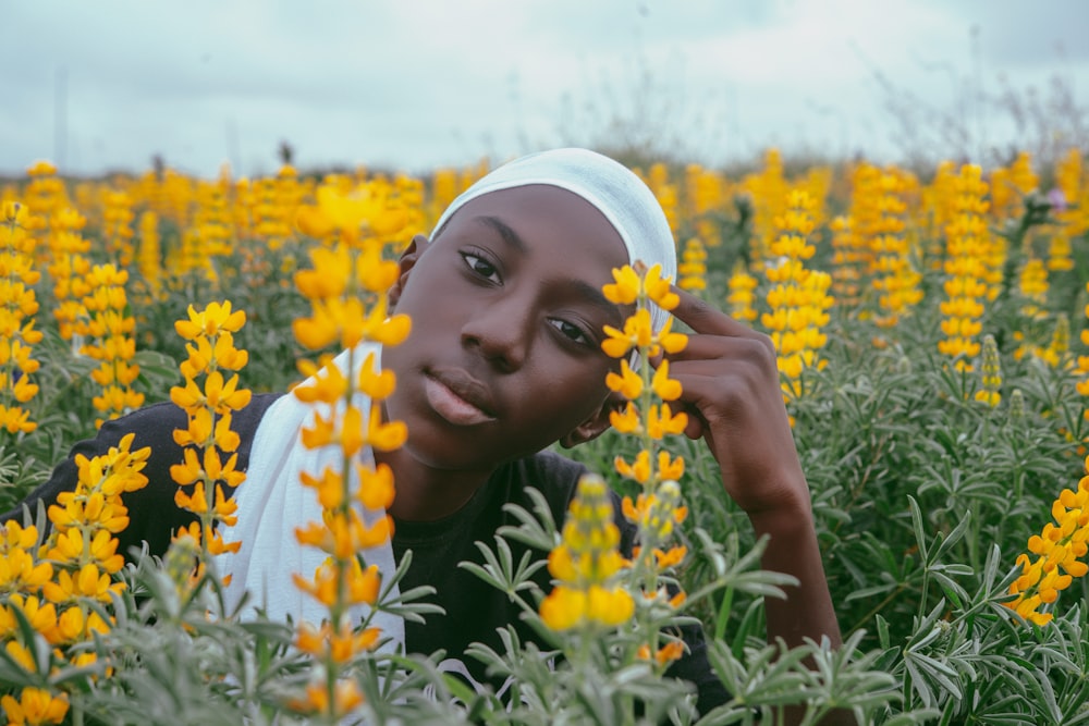 femme en hijab blanc sur le champ de fleurs jaunes pendant la journée