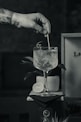 grayscale photo of person pouring water on clear drinking glass