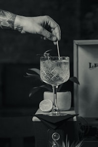 grayscale photo of person pouring water on clear drinking glass