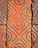 A close-up view of textured terracotta tiles with circular and diamond patterns, showing signs of aging and weathering.