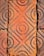 A close-up view of textured terracotta tiles with circular and diamond patterns, showing signs of aging and weathering.