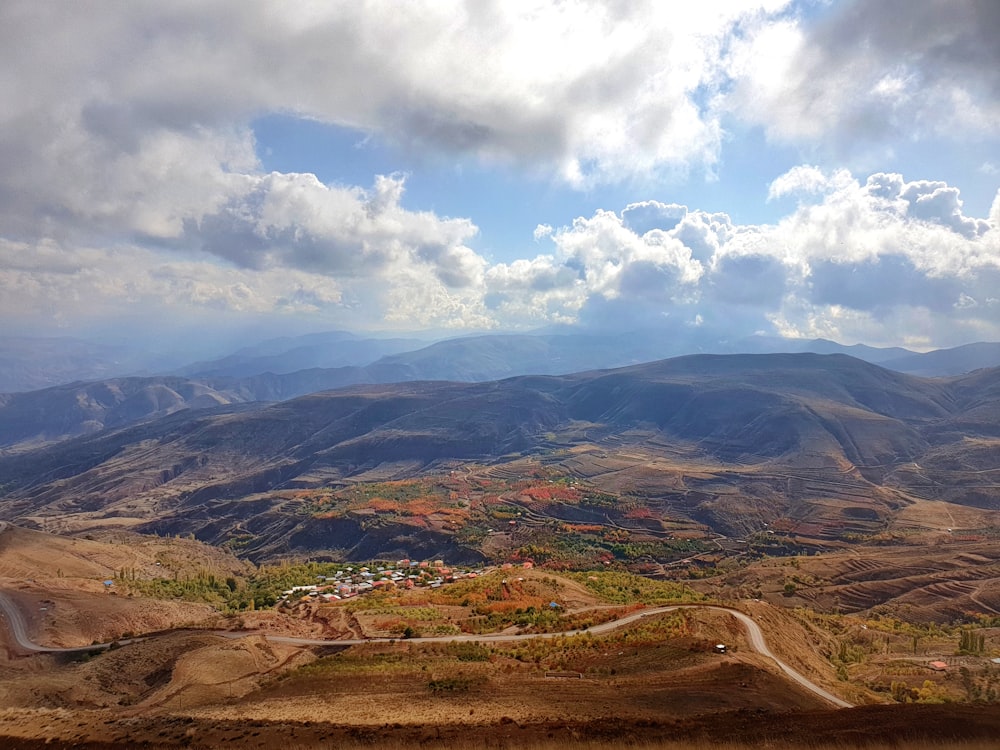 brown and green mountains under white clouds and blue sky during daytime