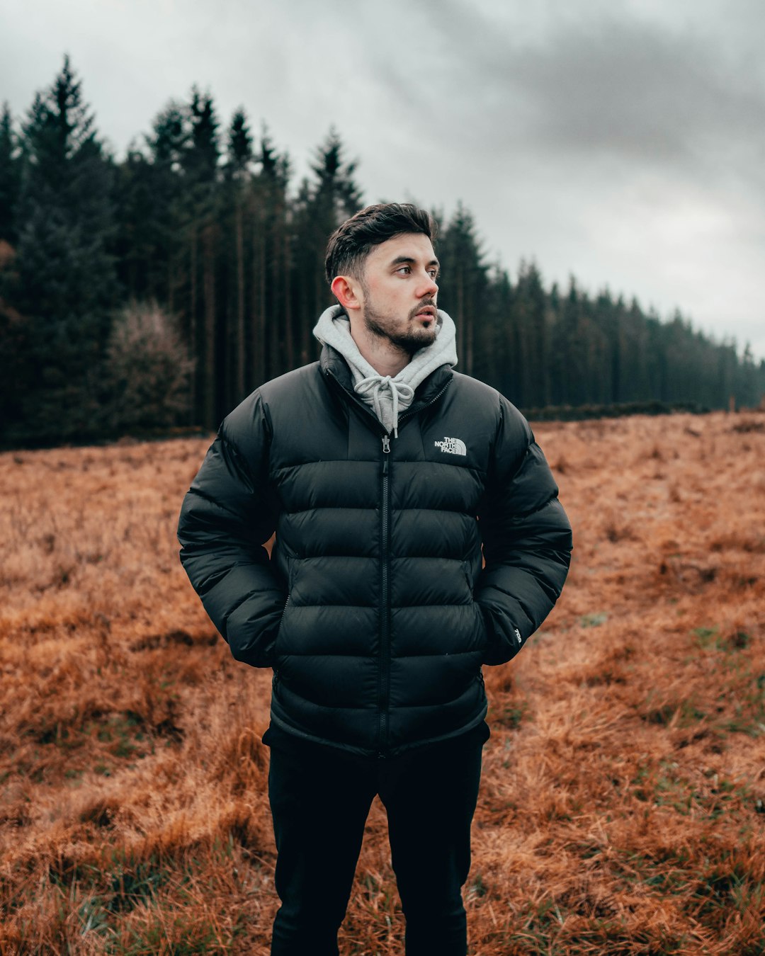 man in black bubble jacket standing on brown grass field during daytime