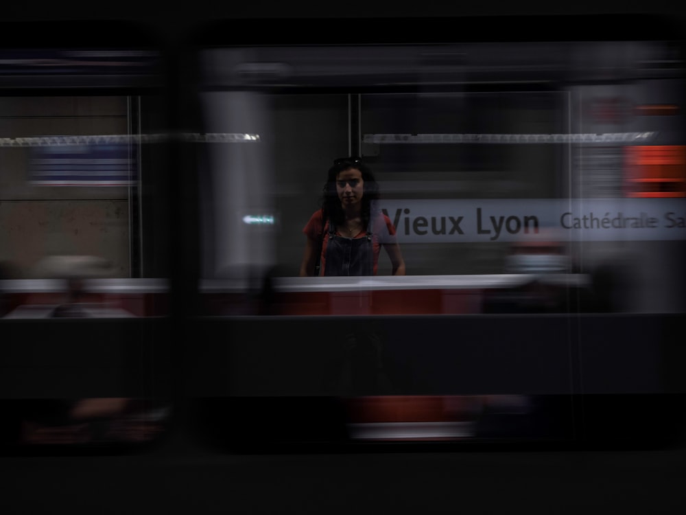 woman in black jacket standing beside glass window