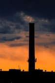 Wide shot of a tall chimney stack against a clear blue sky at sunset.