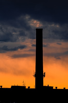 Wide shot of a tall chimney stack against a clear blue sky at sunset.