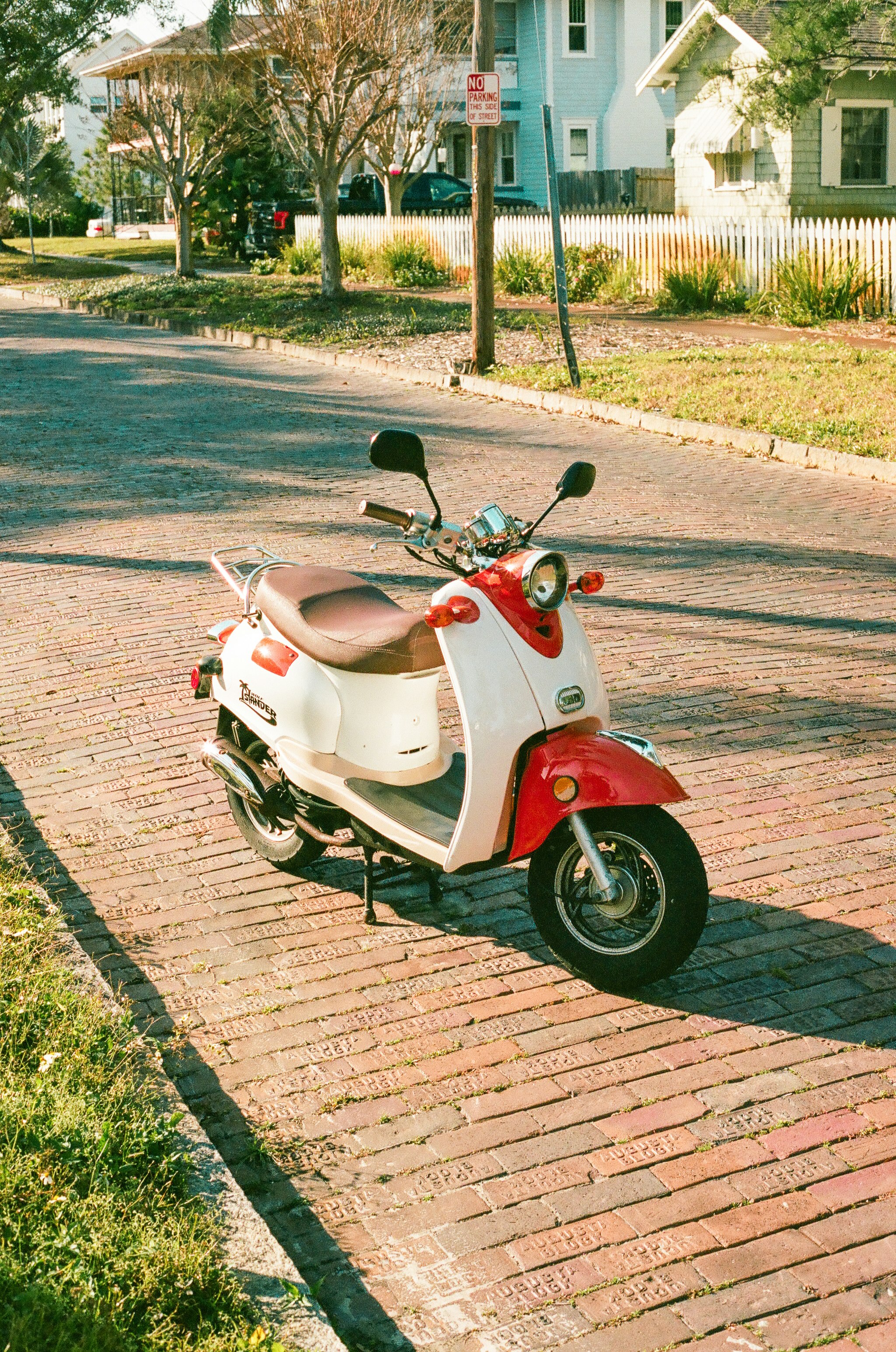red and white motor scooter parked on gray concrete road during daytime