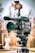A professional video camera is mounted on a tripod, equipped with various attachments including a microphone and a mounted light with an orange filter. The background is blurred, suggesting an outdoor setting on a clear day.
