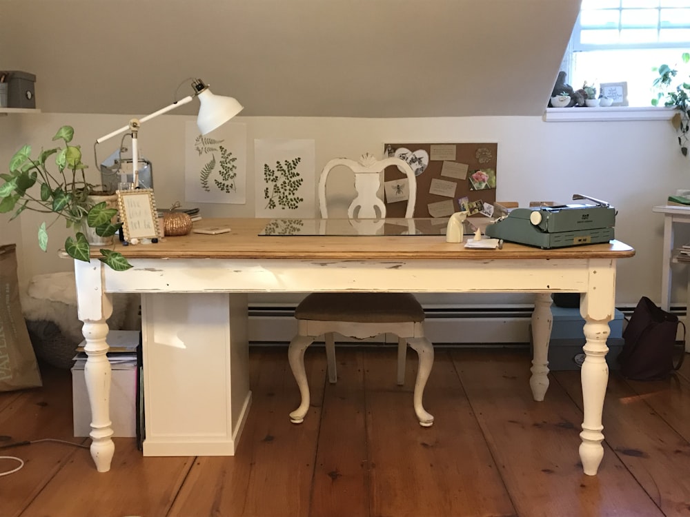 a room with a desk, chair, lamp and pictures on the wall