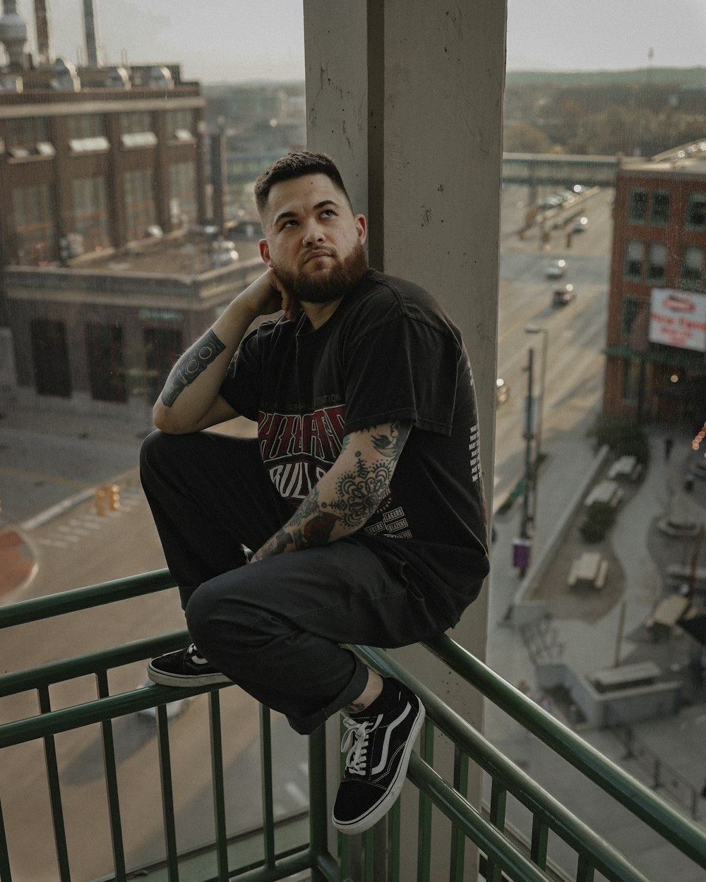 a man with tattoos sitting on a balcony