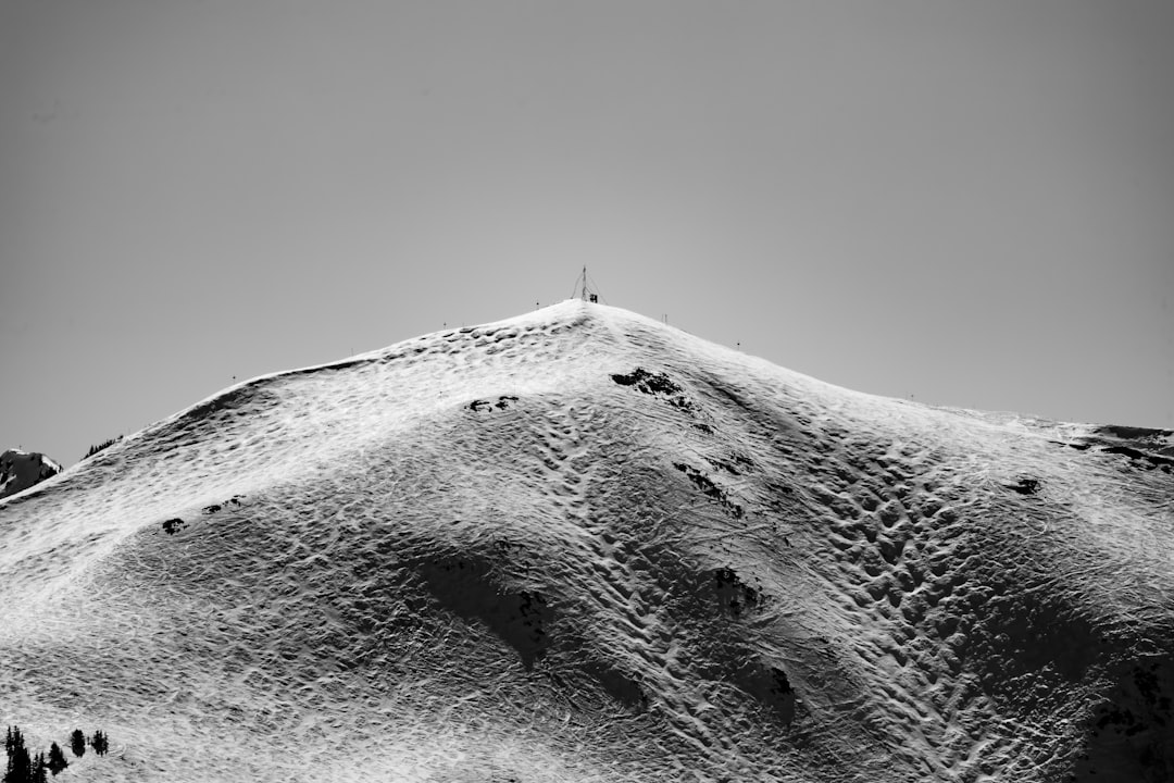 grayscale photo of person standing on top of mountain