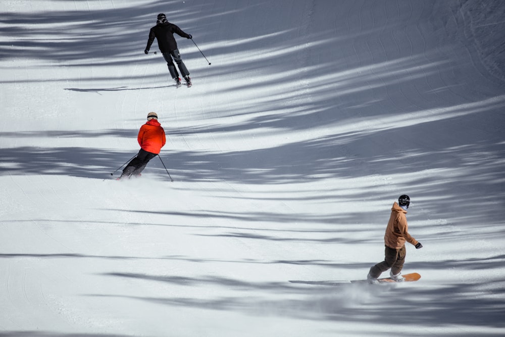 homme en veste marron et pantalon gris tenant des bâtons de ski sur un sol enneigé pendant la journée