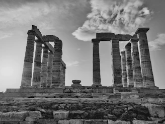 A black-and-white photo of an ancient ruin with crumbling stone columns.