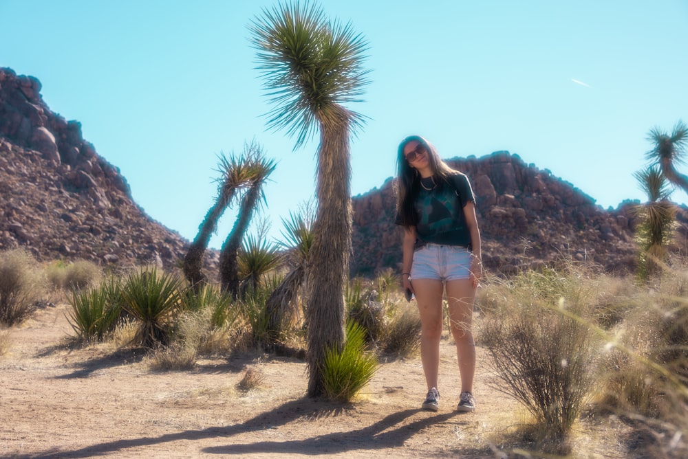 woman in black shirt standing near green palm tree during daytime