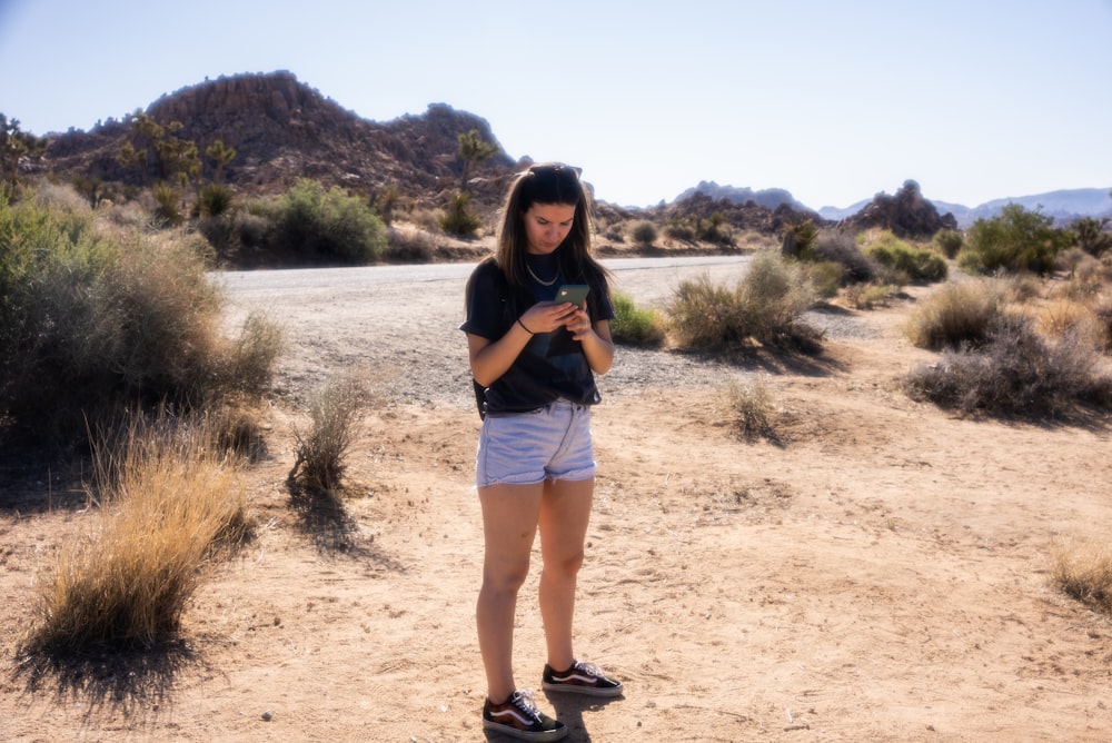 woman in black t-shirt and white shorts standing on brown sand during daytime