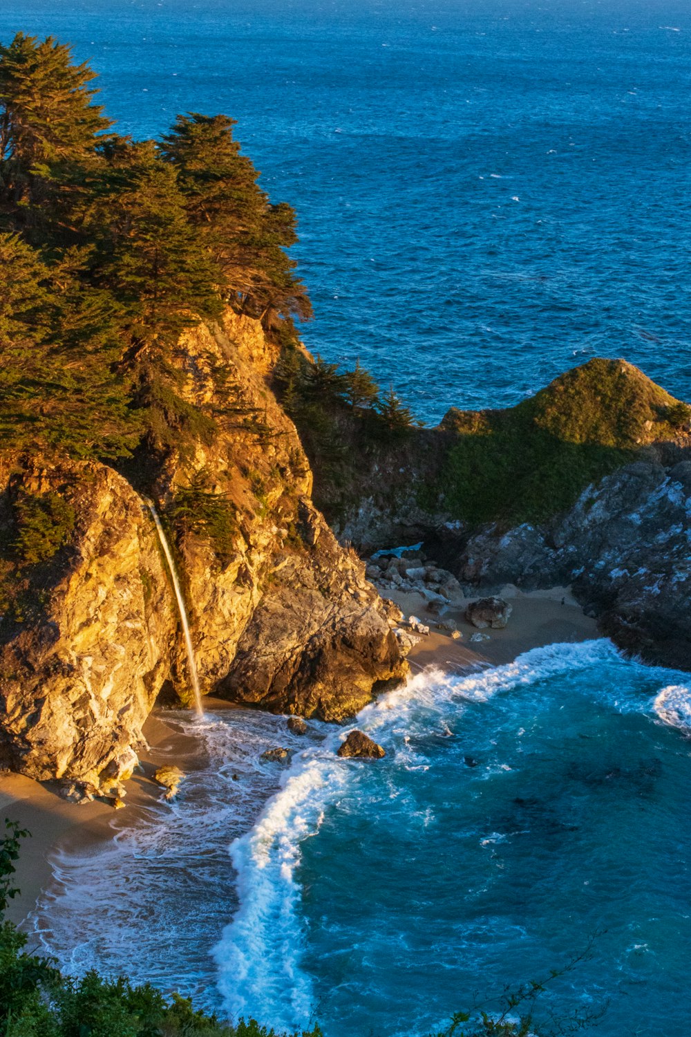 brown and green rock formation beside blue sea during daytime