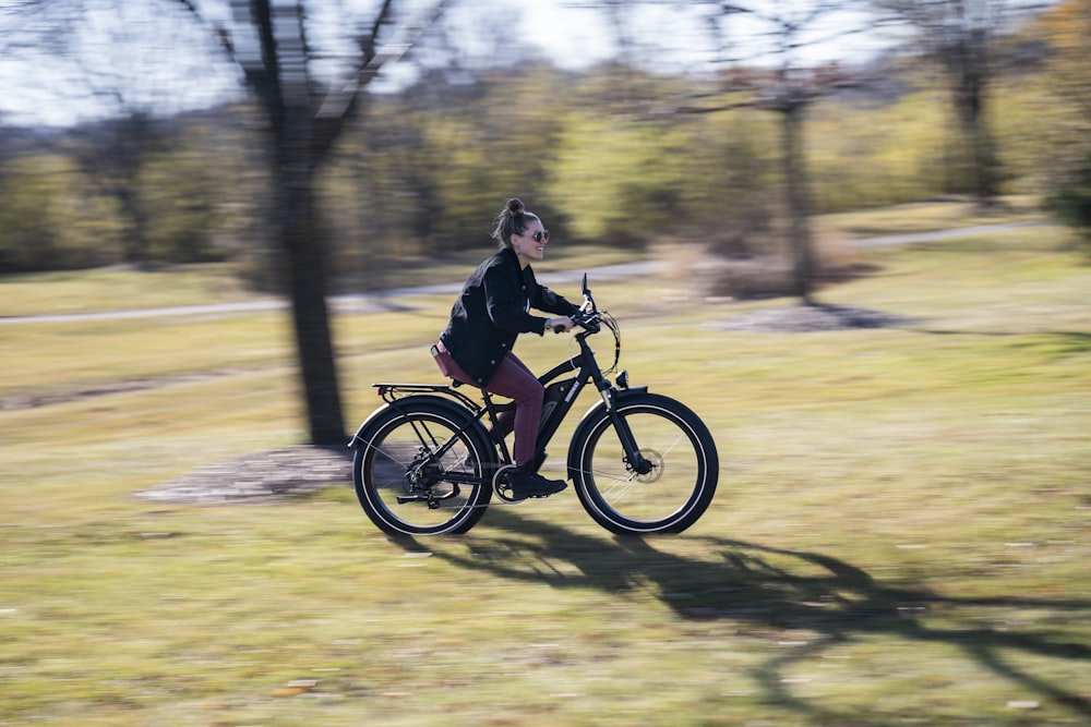 girl in black jacket riding on black motorcycle on brown field during daytime