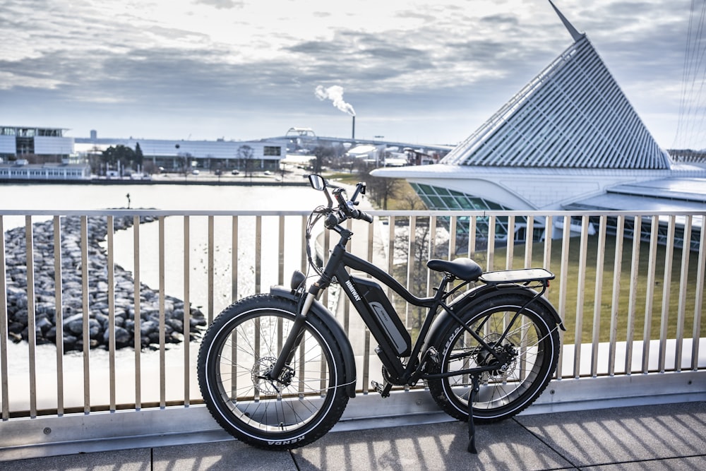 black and gray bicycle beside blue wooden fence during daytime