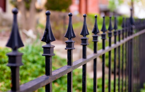 black metal fence near green grass during daytime