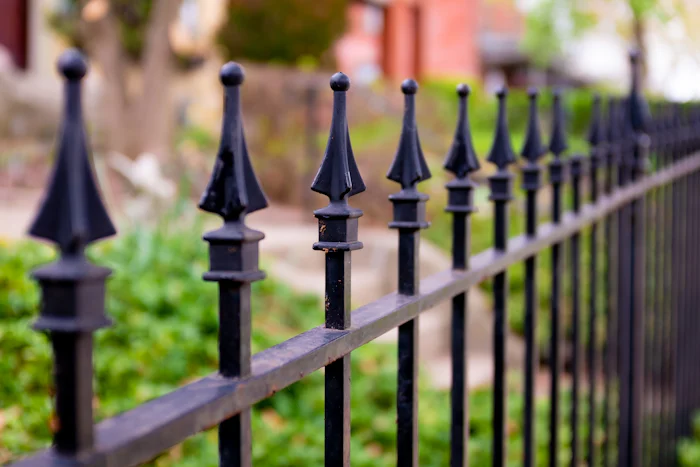 Black metal iron fence installed along a grass lawn