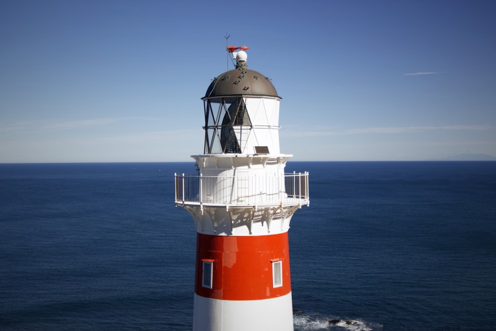 weißer und roter Leuchtturm am Meer tagsüber