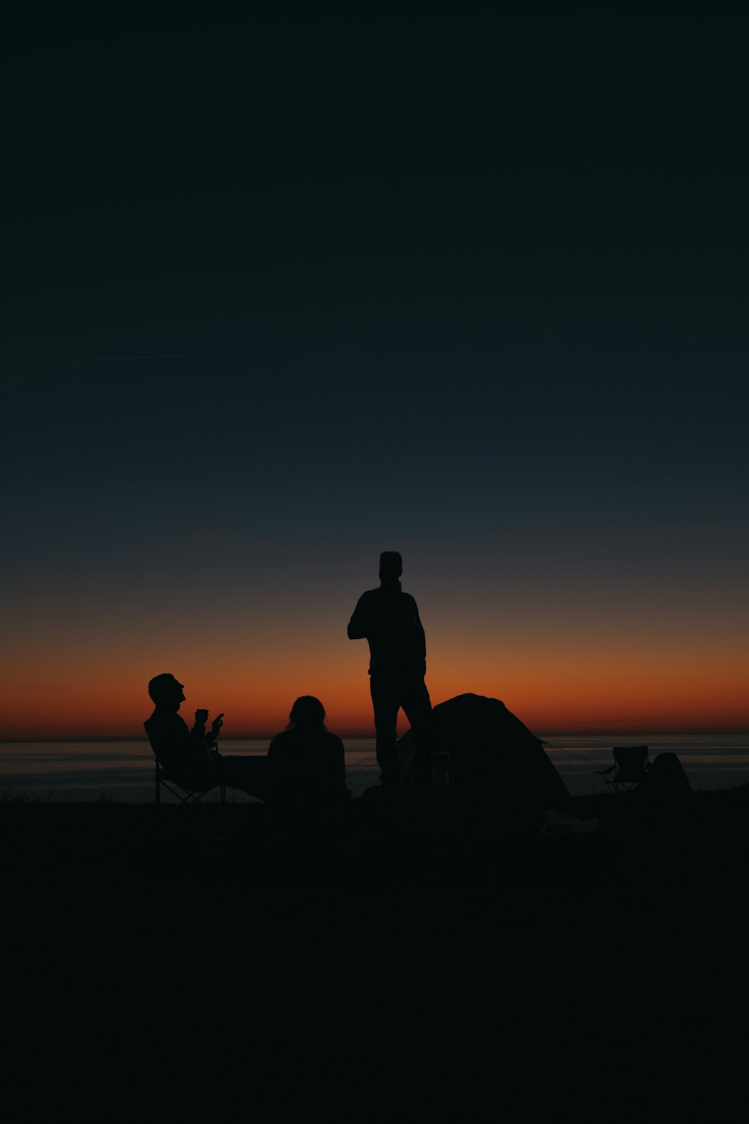 silhouette of people sitting on beach during sunset