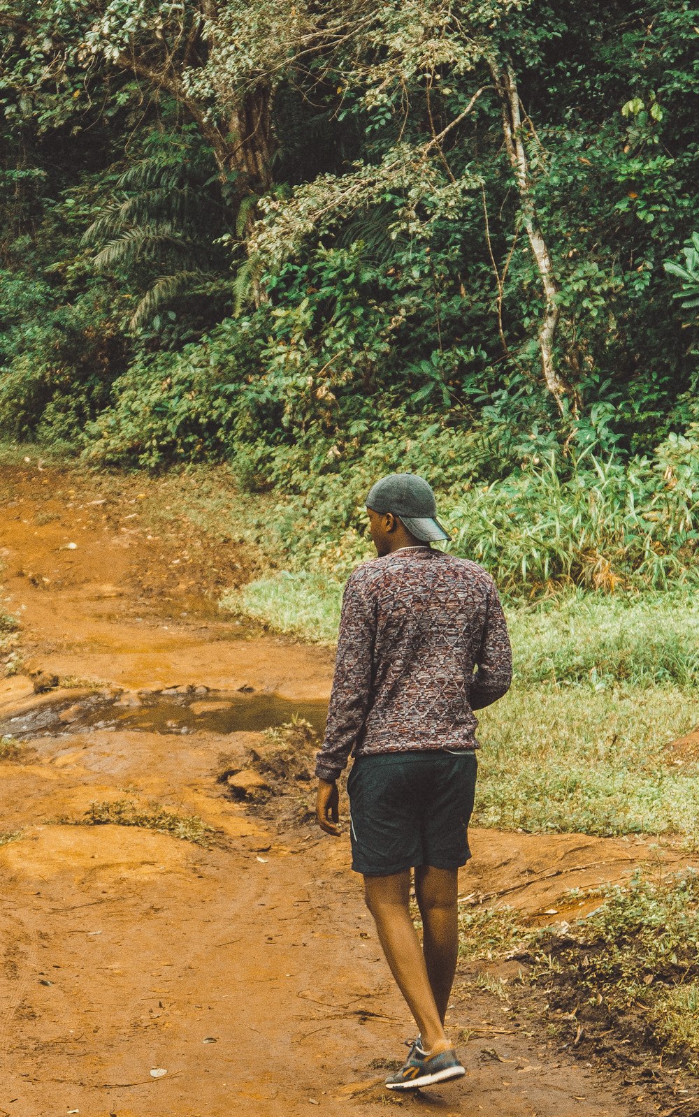 man in grey and black long sleeve shirt walking on dirt road during daytime