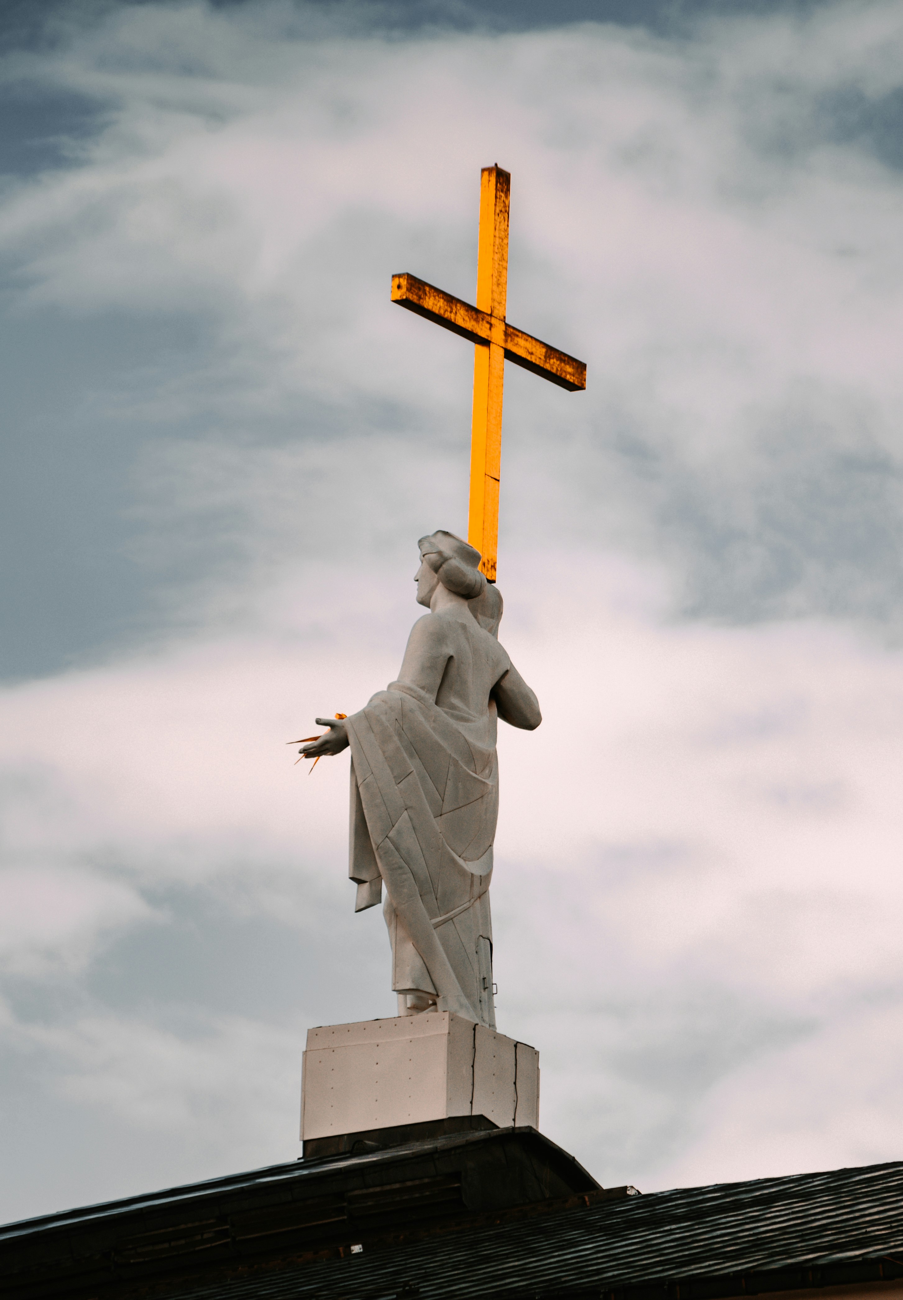 man in robe holding cross statue