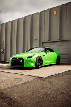 green porsche 911 parked beside gray wall