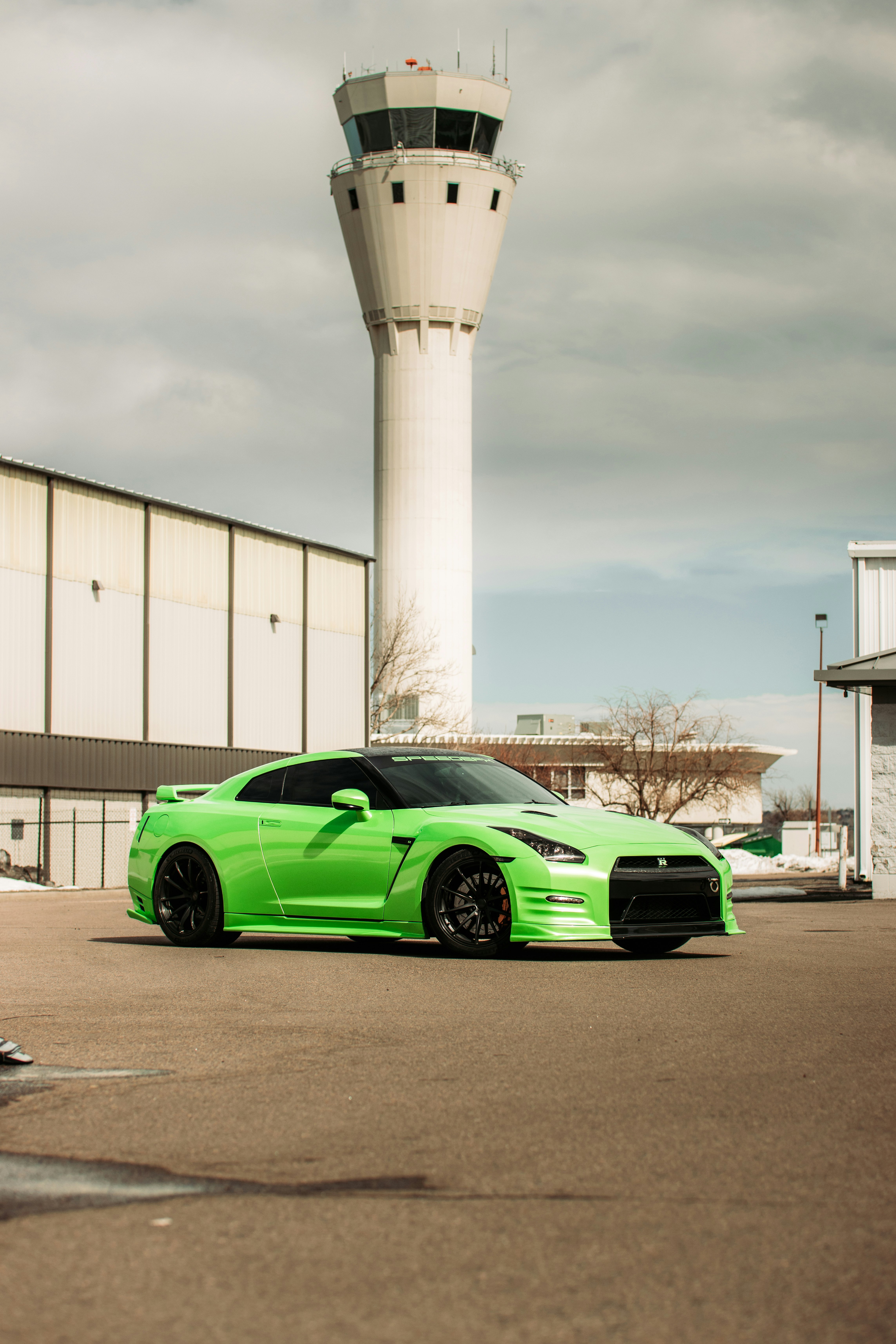 green coupe parked near white building