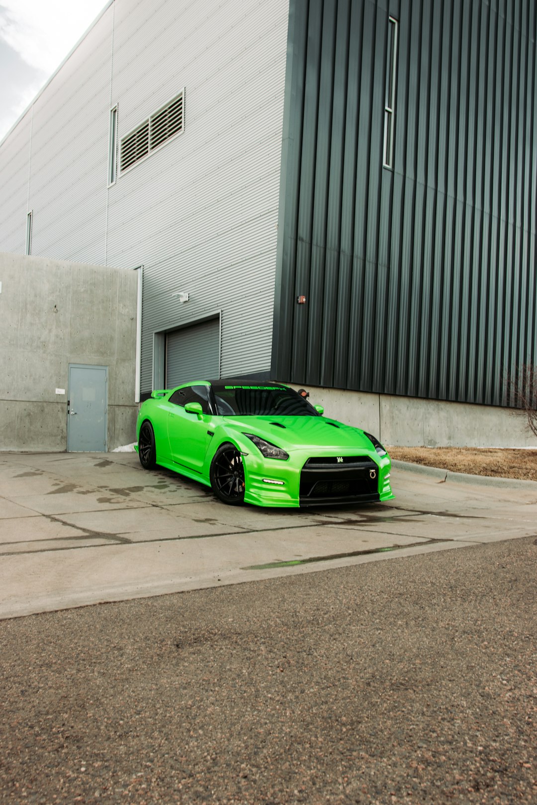 green ferrari sports car parked beside black metal gate