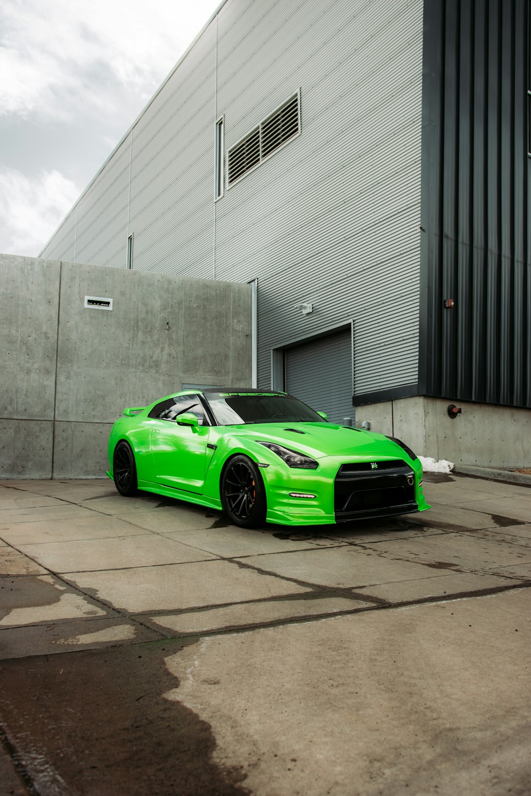 green ferrari sports car parked beside gray building