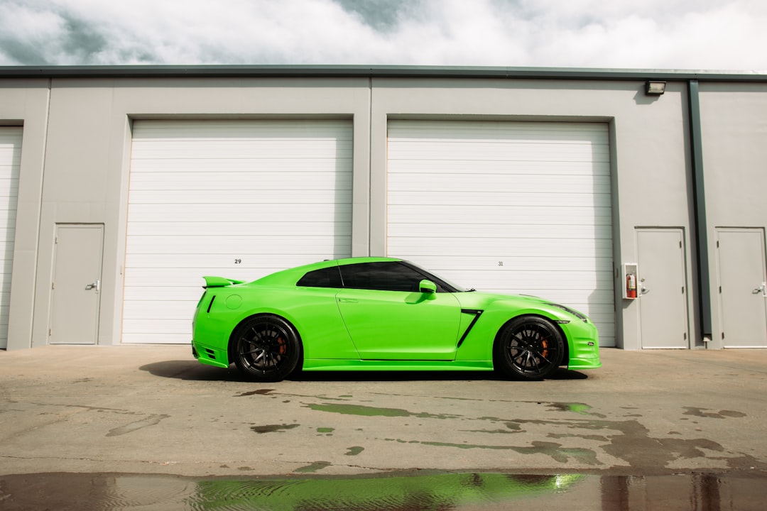 green coupe parked in front of white garage door