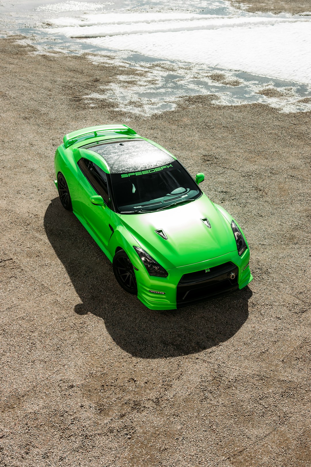 green car on gray sand during daytime