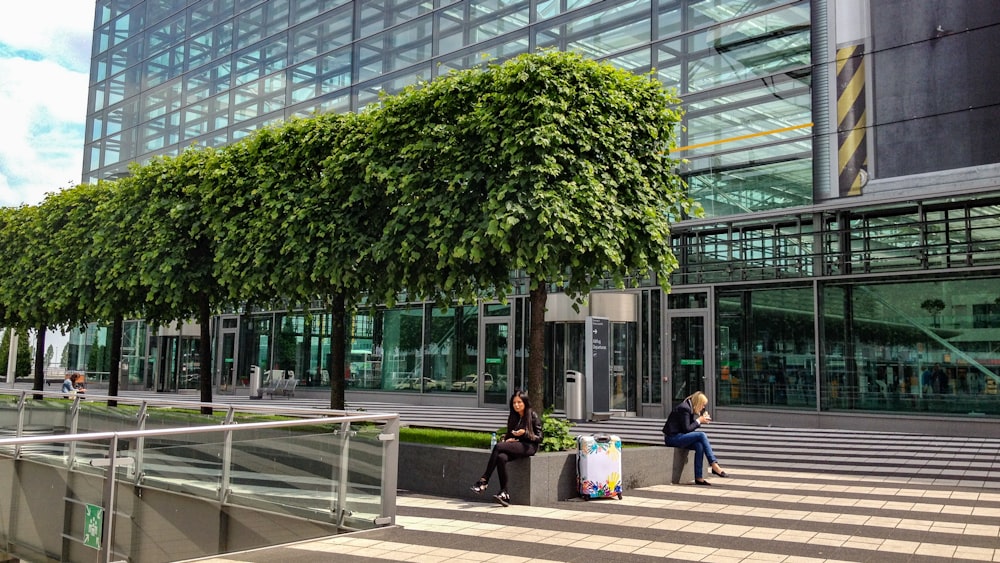 woman in black jacket sitting on bench near green trees during daytime