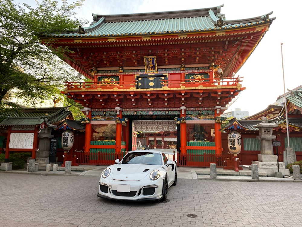 Coche blanco estacionado cerca del templo rojo y marrón durante el día