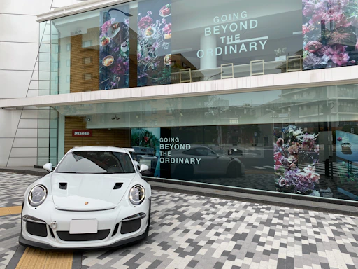 A sleek, modern storefront of RR Garagem with tinted windows reflecting the cityscape.
