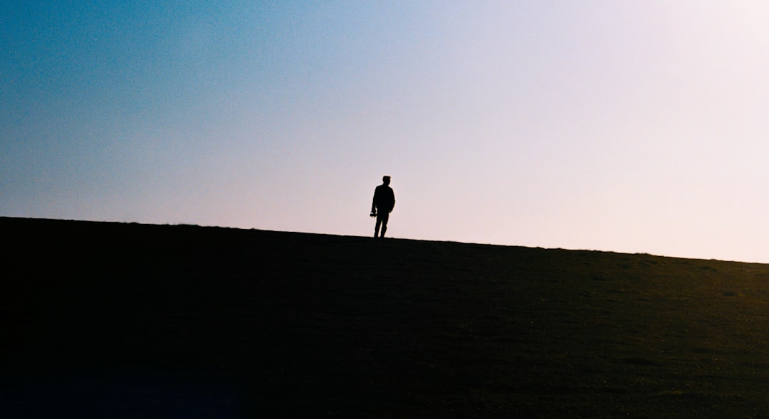 silhouette of 2 person walking on the field during daytime