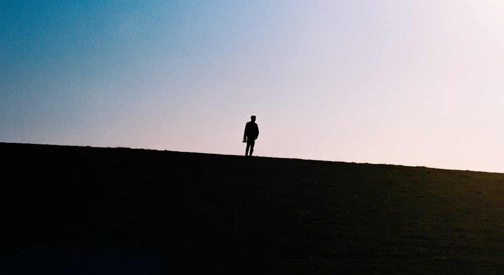 silhouette of 2 person walking on the field during daytime